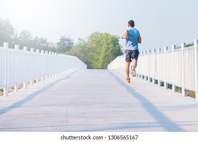 young man runner running on running road in city park