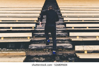 Young man runner in sport clothes running climbing stairs in the stadium - Shutterstock ID 526809604