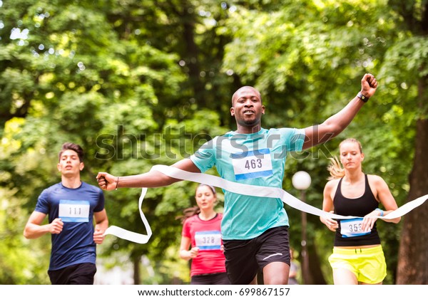 Young\
man running in the crowd crossing the finish\
line.