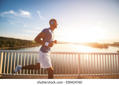 A young man running on the bridge along a river. Lens flare, warm tones. - Powered by Shutterstock