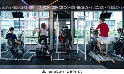 Young man running on treadmill wearing surgical mask & latex rubber gloves, COVID-19 pandemic social distancing rules while working out in  a gym and have Acrylic Partition , social distancing concept - Powered by Shutterstock