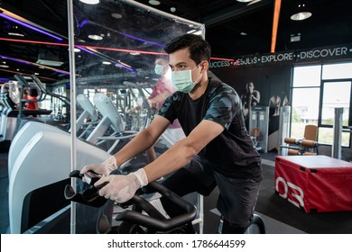 Young man running on treadmill wearing surgical mask & latex rubber gloves, COVID-19 pandemic social distancing rules while working out in  a gym and have Acrylic Partition , 
social distancing concep - Powered by Shutterstock