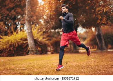 Young Man Running At Park During Autumn Morning