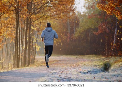 Young Man Running At Park During Autumn Morning