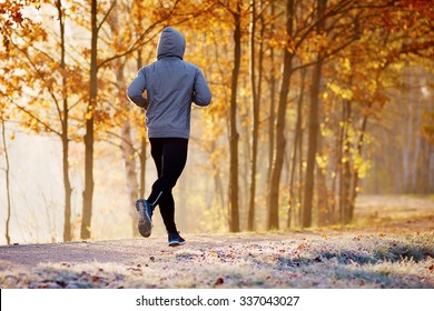 Young Man Running In The Park During Autumn Morning