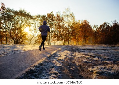 Young Man Running At Park During Cold Winter Morning