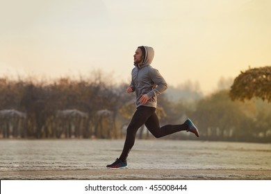 Young Man Running At Park During Winter, Autumn Morning