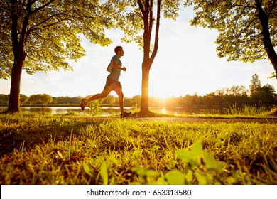 Young Man Running In Park During Sunset