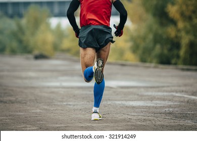 Young Man Runs Through Streets. While Running It On Compression Stockings And Arm Warmer