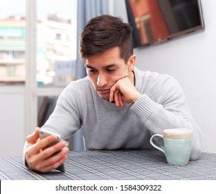 Young Man Is Sad Sitting With Phone Because She Is Alone At Home