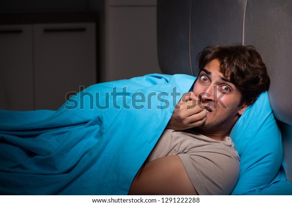 Young man scared\
in his bed having\
nightmares