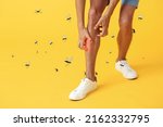 Young man scratching himself and many mosquitoes on yellow background