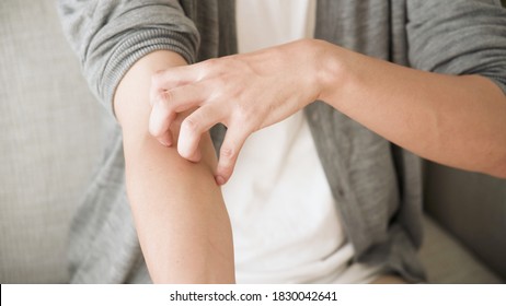 Young Man Is Scratching His Arm