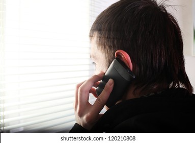 Young Man See Through The Jalousie And Talking On Mobile Phone