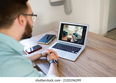 Young Man Seen From Behind Watching A Virtual Tour Video On The Laptop. Caucasian Man Looking To Buy A New Property