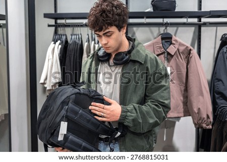Young man selecting backpack in retail store, Teenage boy choosing backpack in store, back to school and shopping, ravel and consumer purchase decision concept.