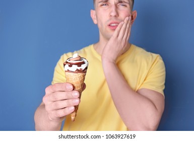 Young Man With Sensitive Teeth And Cold Ice Cream On Color Background