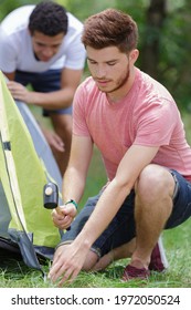 Young Man Setting Up Camp Tent For Camping Trip