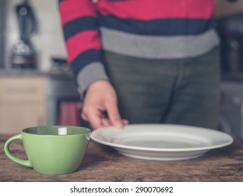 A Young Man Is Setting The Table In A Kitchen With A Plate