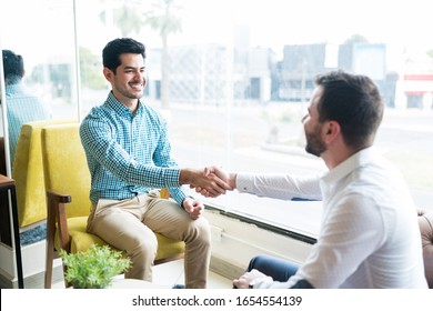 Young Man Shaking Hands With Business Partner And Coming To An Agreement In An Office