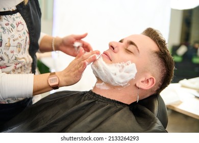 Young Man Shaving With Straight Edge Razor By Hairdresser In Barbershop