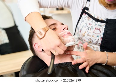 Young Man Shaving With Straight Edge Razor By Hairdresser In Barbershop