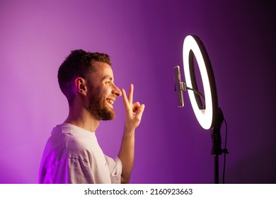 Young Man Shoots A Video On A Phone With A Ring Lamp, Portrait In Color Light