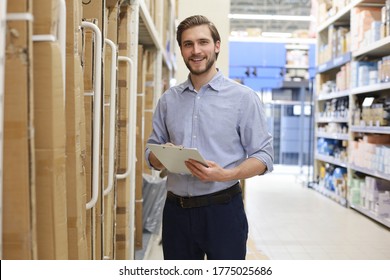 Young Man Shopping Or Working In A Hardware Warehouse Standing Checking Supplies On His Tablet.