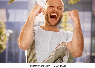 Young Man Shouting With Hapiness Outdoors, Clenching Fists.