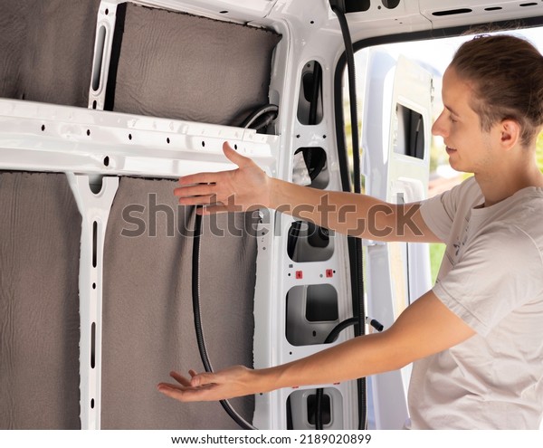 Young man showing his great\
job making the insulation of a camper van for better temperature\
control