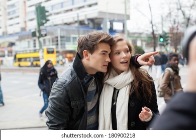 Young Man Showing Something To Woman On City Street