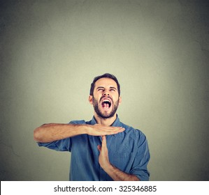 Young Man Showing Time Out Hand Gesture, Frustrated Screaming To Stop Isolated On Grey Wall Background. Too Many Things To Do. Human Emotions Face Expression Reaction