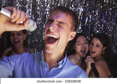 Young Man Singing Into Microphone At Karaoke