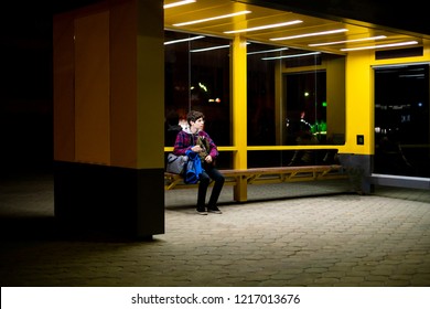 Young Man Sit On The Bus Stop Bench Waiting In The Night