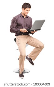 A Young Man Sitiing On A High Chair And Working On A Laptop Isolated On White Background