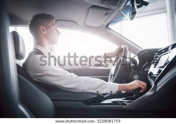 A young man sits in a newly purchased car at the
wheel, a successful purchase