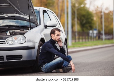 A Young Man Sits On The Side Of The Road And Calls The Evacuation Service, Because His Car Broke Down 