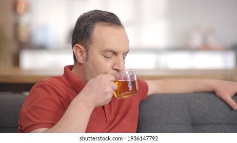 Young Man Sitting Alone At Home Drinking Herbal Tea. Portrait Of Man Drinking Herbal Tea.