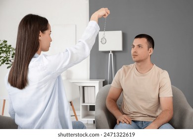 Young man sitting in armchair during hypnosis session at psychologist's office - Powered by Shutterstock