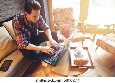 Young Man Sitting At A Cafe, Using A Laptop