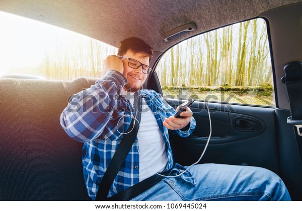 young man sitting in car at backseats. man using\
phone in car. car travel\
concept
