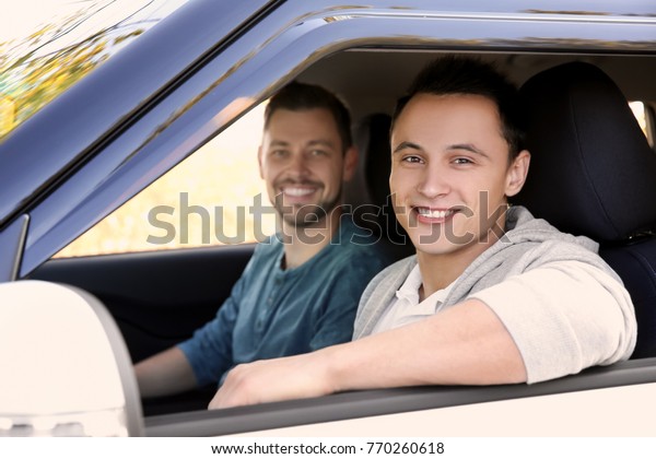 Young man\
sitting in car with driving\
instructor
