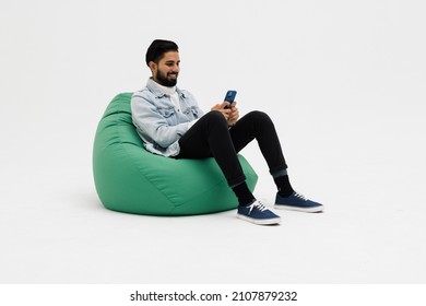 Young man sitting comfy soft violet armchair holding telephone chatting colleagues wear specs casual denim outfit isolated grey color background - Shutterstock ID 2107879232