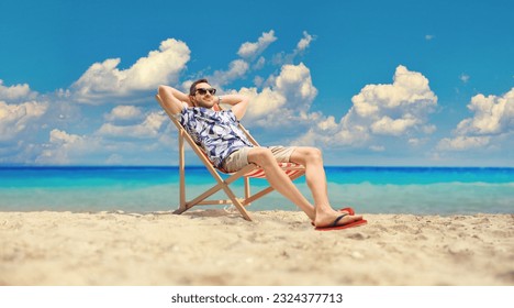Young man sitting at a deck chair by the sea - Powered by Shutterstock
