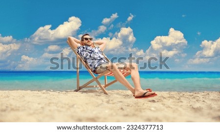 Young man sitting at a deck chair by the sea