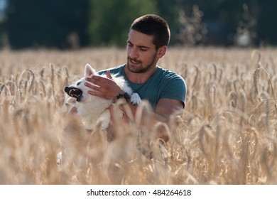 Young Man Sitting With Dog German Spitz In Harvested Field - He Is Going Crazy