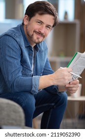 Young Man Sitting Doing A Crossword Puzzle