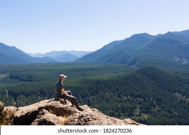 Young Man Sitting And Enjoying The Beautiful View Of Cascade Range, Washington State, Usa, Healthy Active Lifestyle Concept