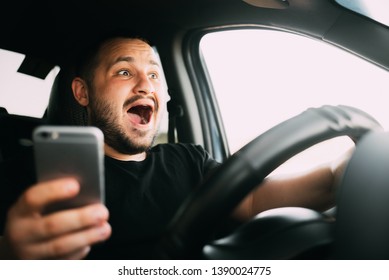 Young man sitting in his car screaming distracted by smartphone texting - Shutterstock ID 1390024775