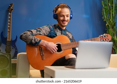 Young Man Sitting In His Room And Watching Guitar Tutorial On Laptop